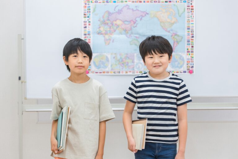 世界地図の前で本を持つ子どもたち